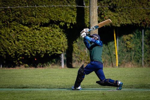 Free Cricketer executes powerful shot during a cricket match on a sunny day. Stock Photo