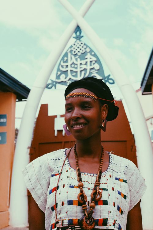 Free Portrait of a smiling African woman wearing traditional attire outdoors. Captured in warm, vibrant tones. Stock Photo