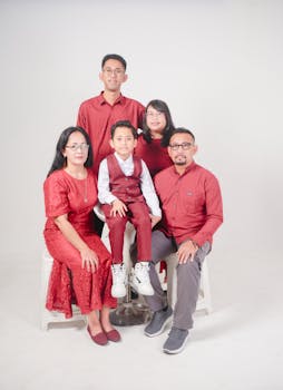 Family portrait session with five members in coordinated red outfits, studio setting.