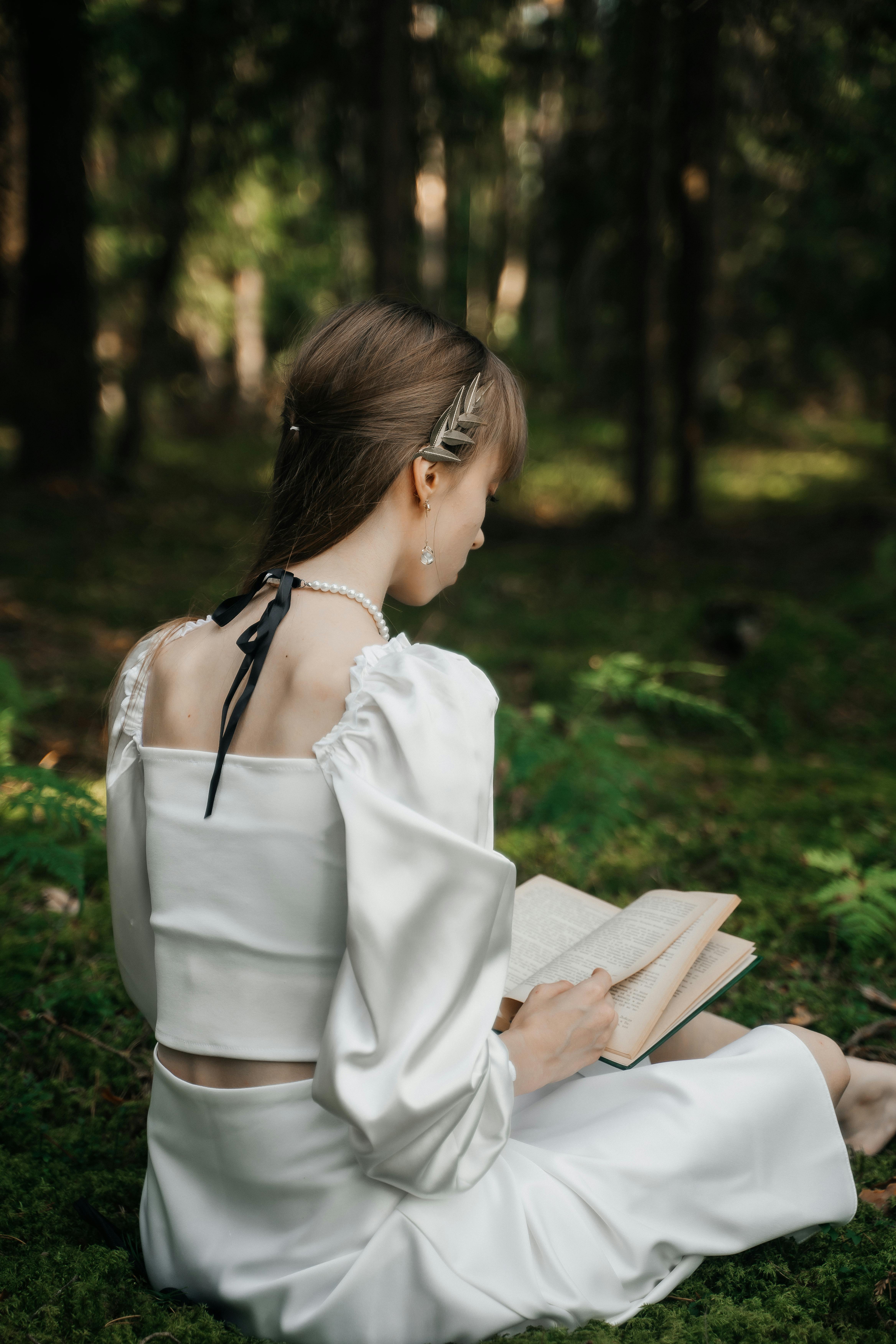 woman reading book in tranquil forest setting