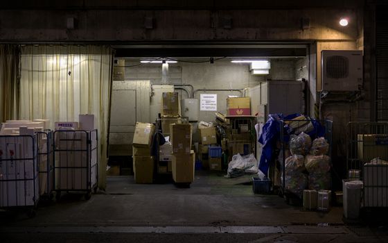 Dimly lit urban waste disposal area at night in Kyoto, Japan, showcasing urban maintenance.