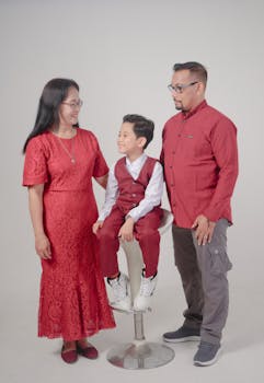 A family portrait with parents and child dressed in red attire, taken in a studio setting.