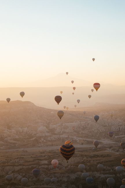 Hot air balloons floating over Cappadocia at sunrise, creating a stunning scenic view.