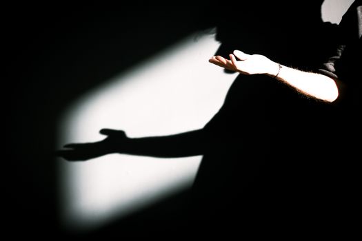 Artistic capture of hands and their shadows on a dark background.