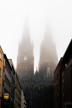 The iconic Cologne Cathedral shrouded in dense fog, creating a mysterious urban landscape.