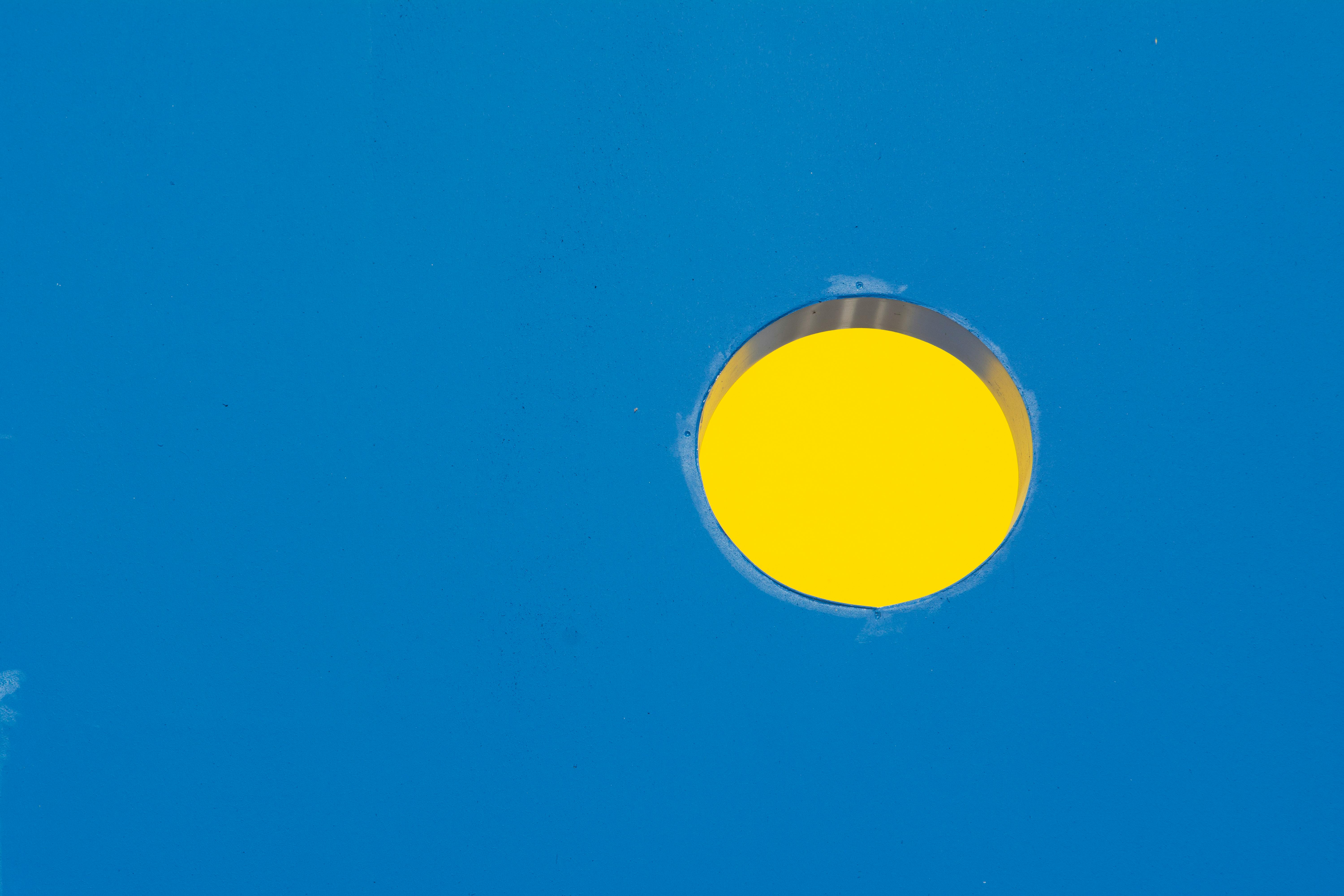 grátis Um círculo amarelo vibrante é colocado sobre um fundo azul sólido, criando um contraste visual impressionante. Foto profissional