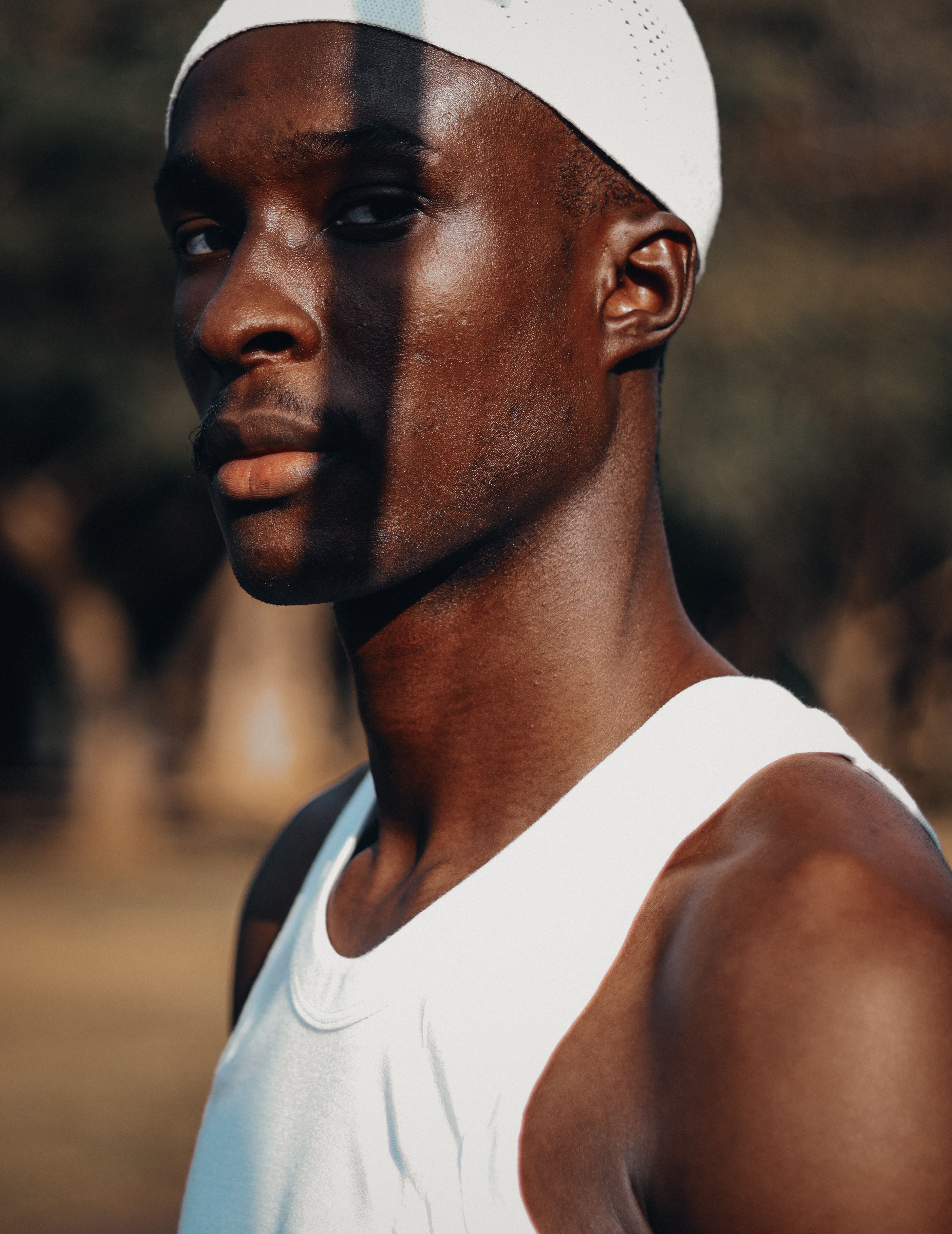 Portrait of a strong, focused athlete in a white tank top with dramatic shadows.