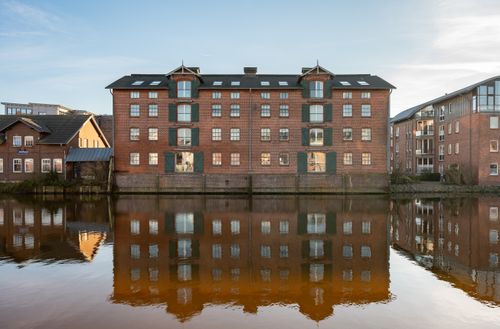 Free Stunning reflection of historic brick buildings in Husum, Germany's calm canal. Stock Photo