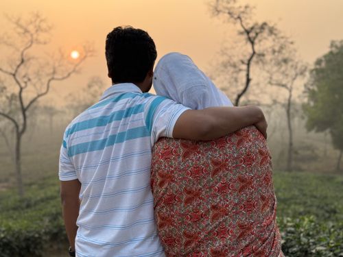 Free A couple embraces, enjoying a serene sunrise in a natural landscape. Stock Photo