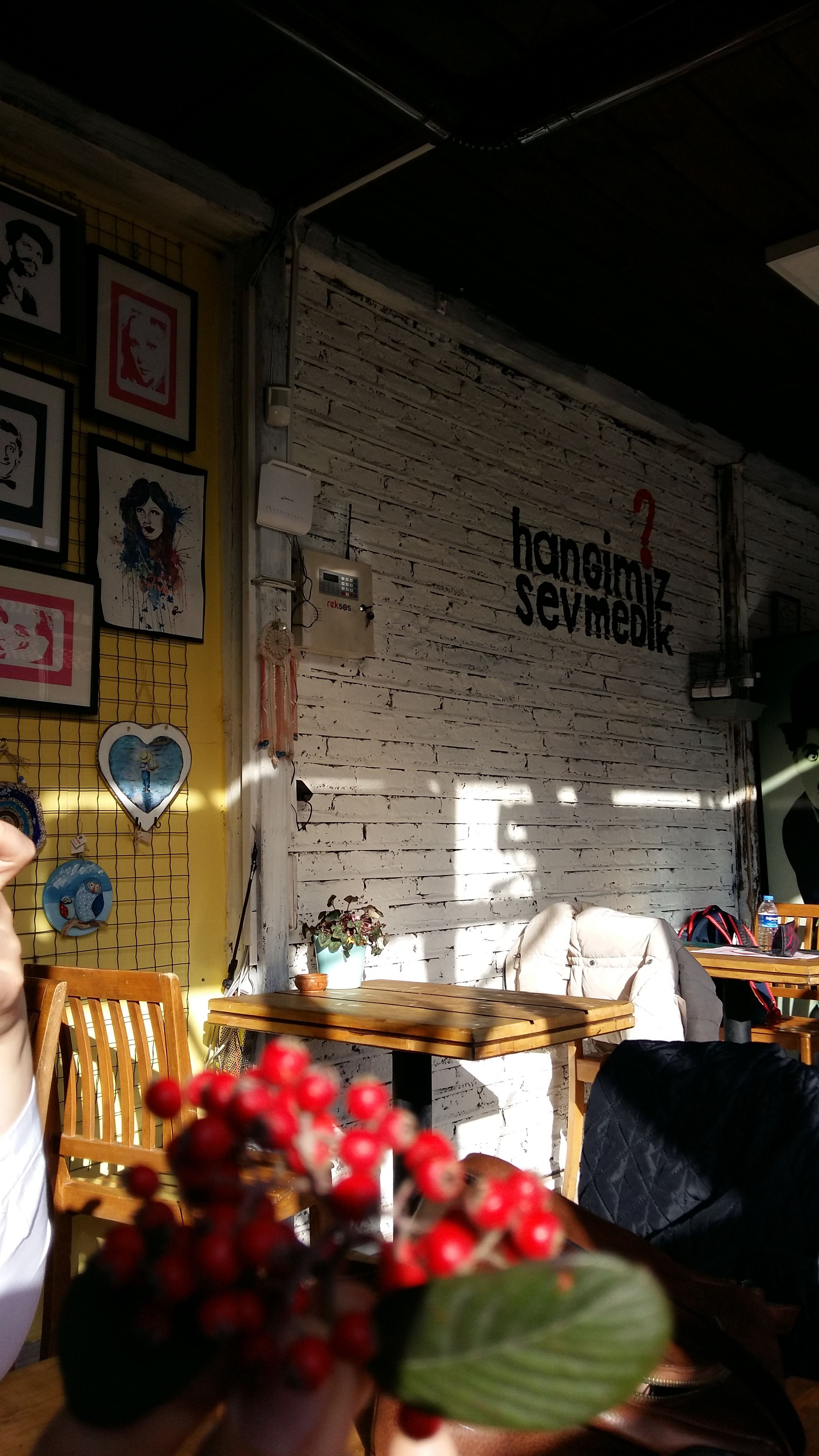 Sunlit cozy cafe interior featuring wall art and a focus on fresh red berries in the foreground.