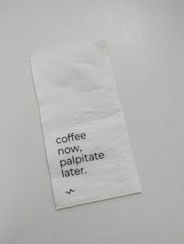 A white napkin with a humorous coffee-related quote.