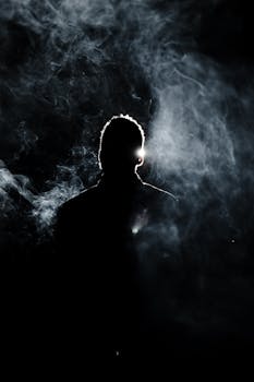 Silhouette of a person enveloped in smoke with a dramatic backlight.