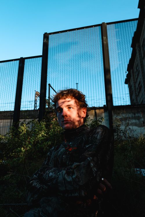 Free Dramatic portrait of a person against a backdrop of an industrial fence. Stock Photo