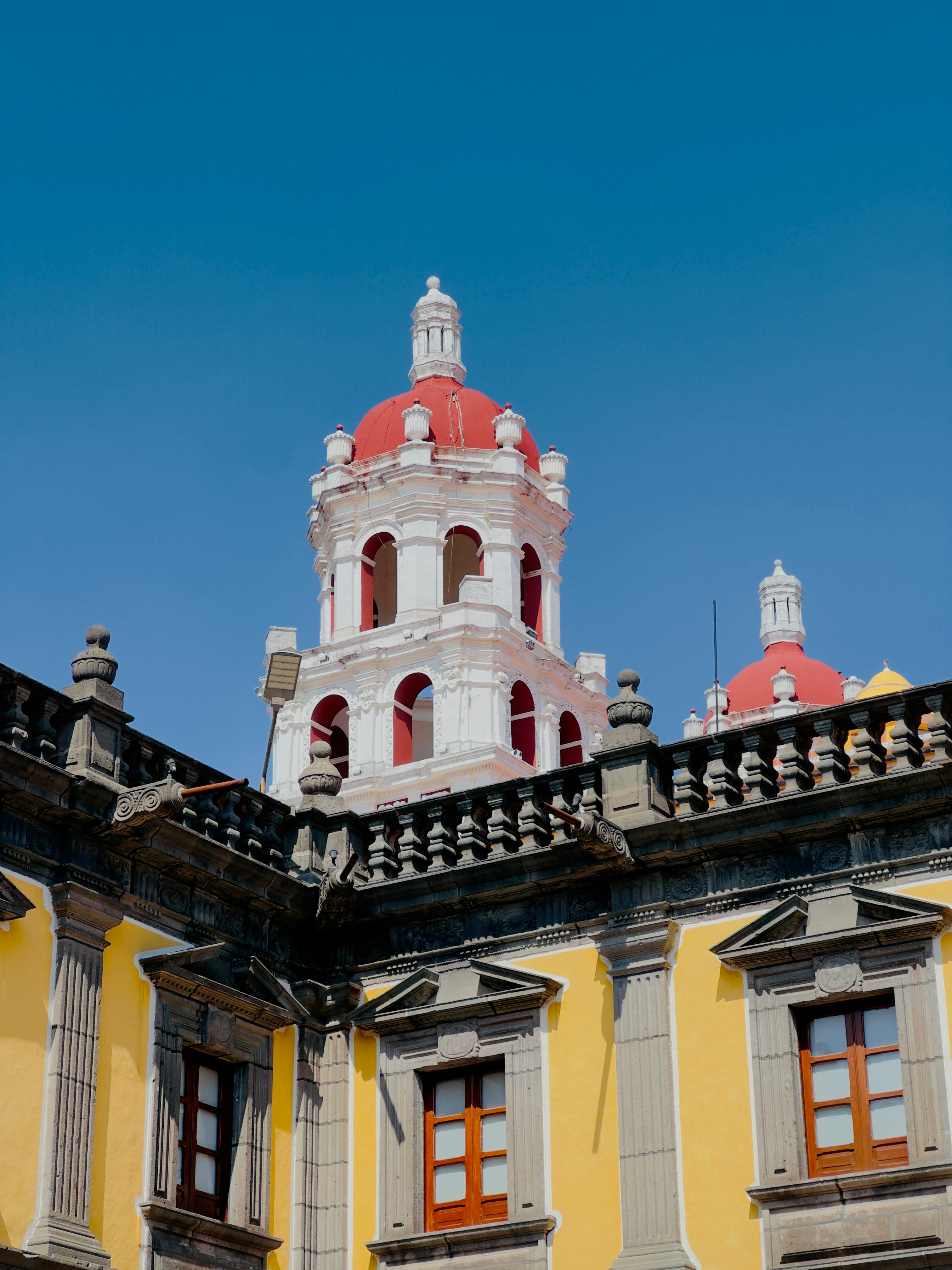Close-up of colorful colonial building with red domes under a clear blue sky in Puebla, Mexico.