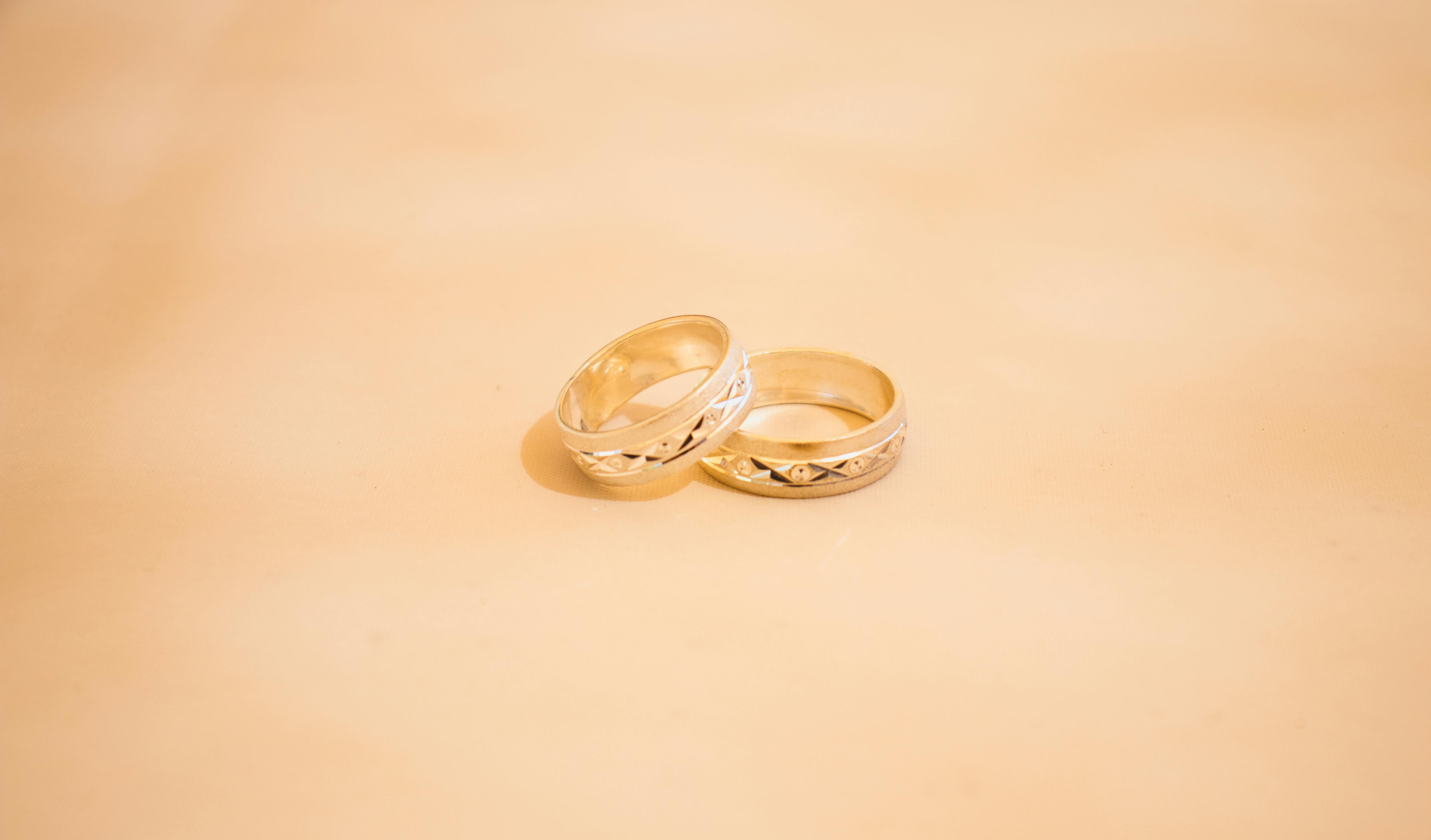 Close-up of two elegant gold wedding rings on a neutral background, symbolizing love and commitment.
