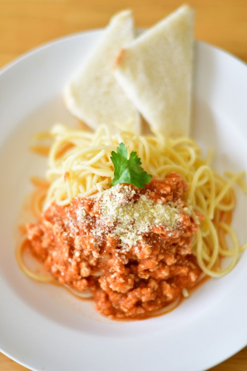Free Plate of spaghetti bolognese topped with cheese and parsley, served with bread slices. Stock Photo
