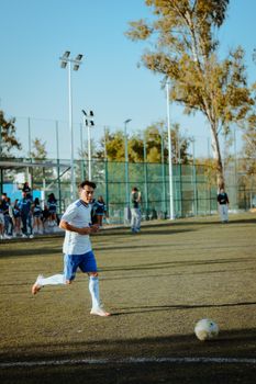 Youth soccer player on a sunny day preparing to kick the ball during a match.