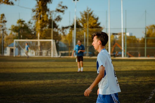 A teenager plays soccer outdoors on a sunny day, enjoying friendly competition.