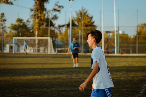 Free A teenager plays soccer outdoors on a sunny day, enjoying friendly competition. Stock Photo