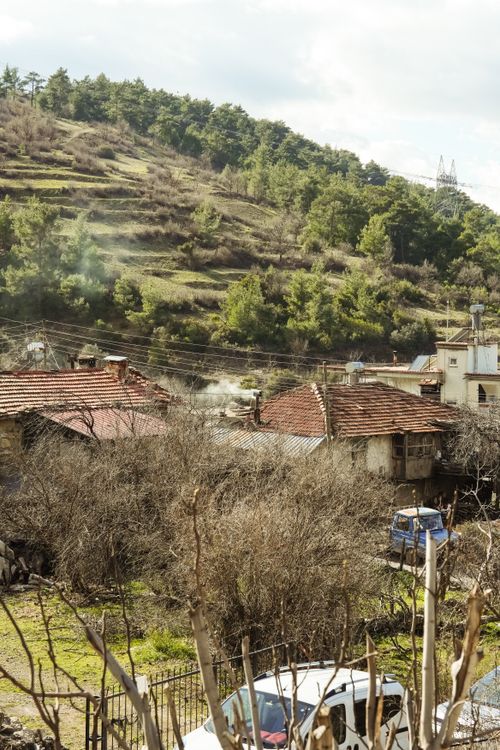 Free Charming rural village nestled against a green hillside under a bright sky. Stock Photo