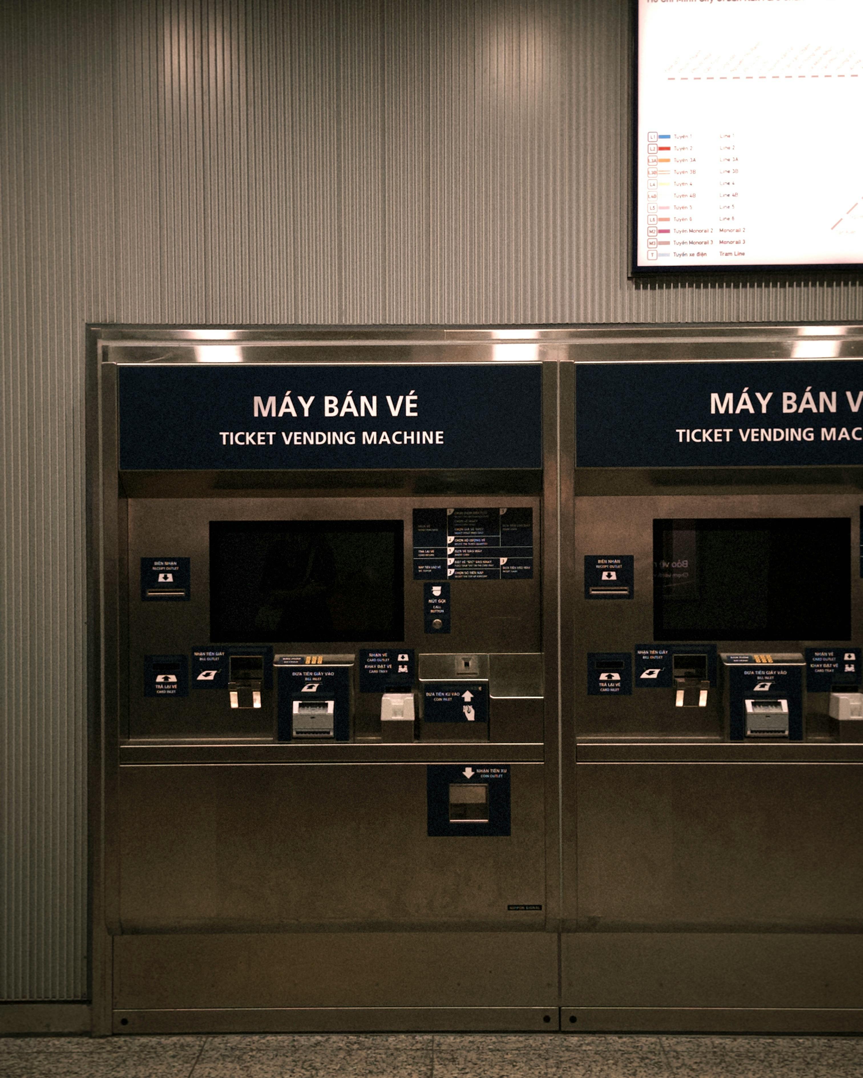 Two modern ticket vending machines with Vietnamese text at a station.