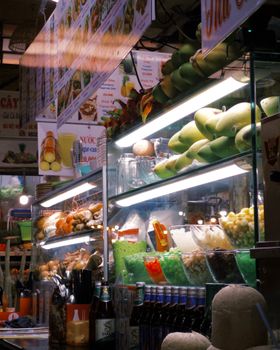 Colorful indoor market showcasing exotic fruits and beverages in glass cases.