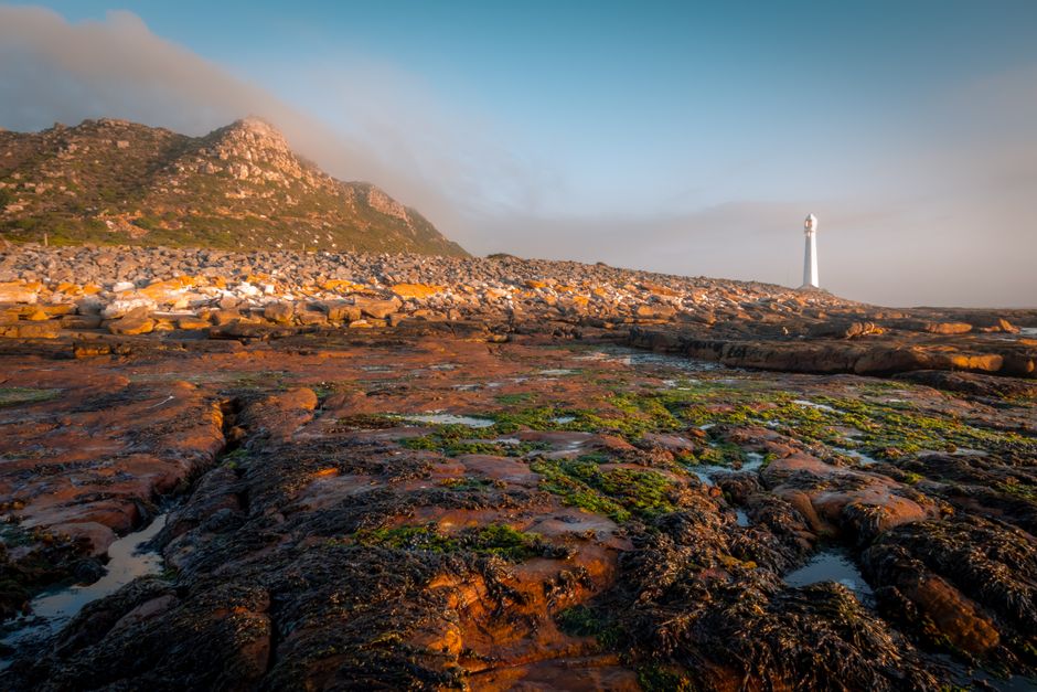 Cape Point's dramatic landscape at sunrise with a solitary lighthouse.