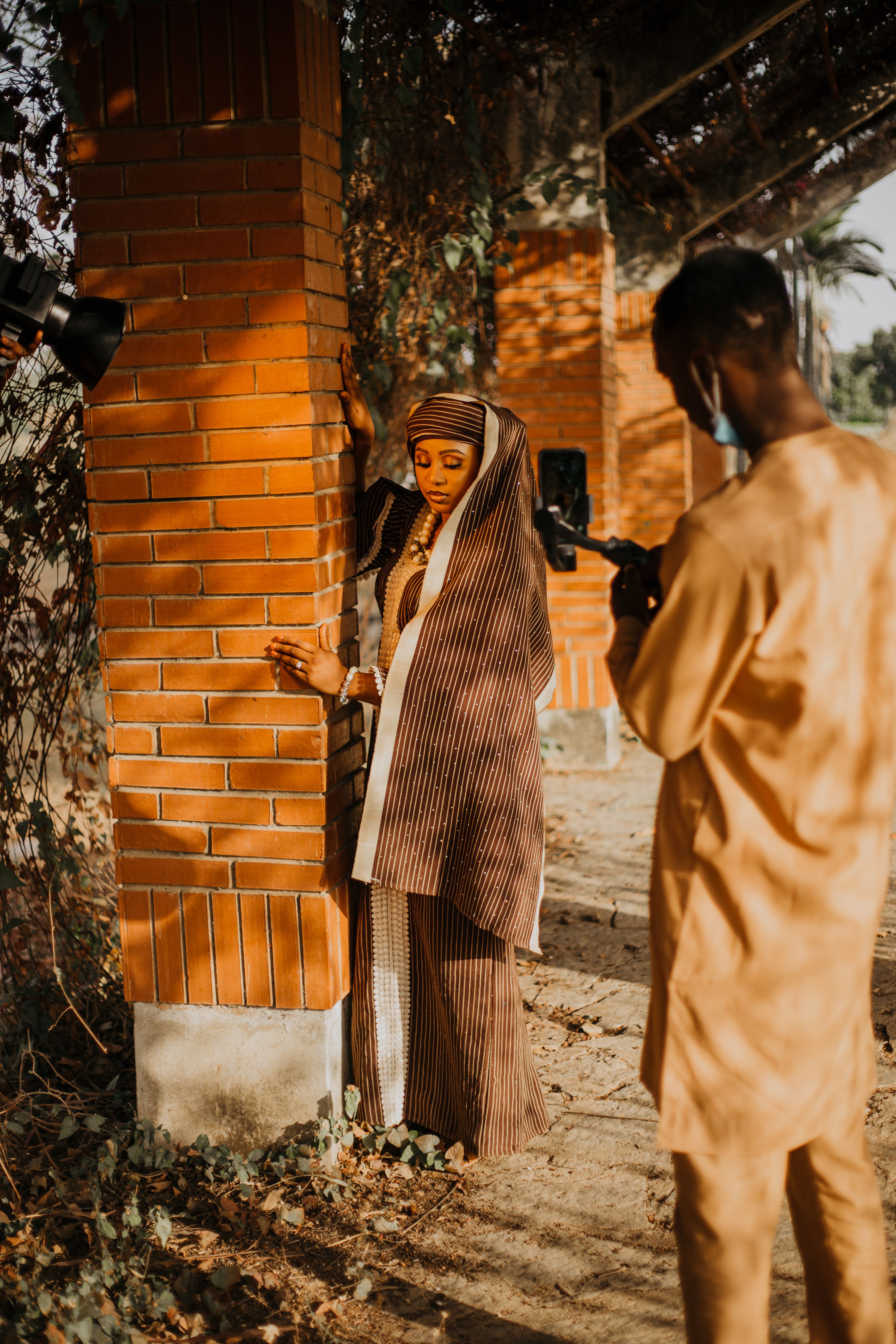 A woman in traditional attire poses outdoors during a photoshoot in Zaria, Nigeria.