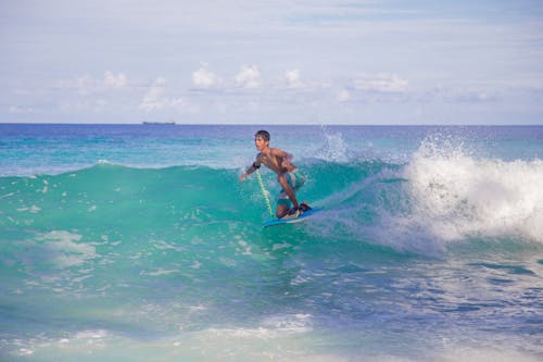 Free Photo of a Topless Man Surfboarding on Blue Waves Stock Photo