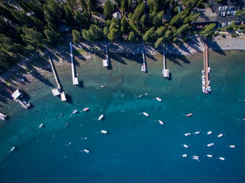 Free A stunning aerial shot of boats by a pier on Lake Tahoe, surrounded by lush forests and clear blue water. Stock Photo