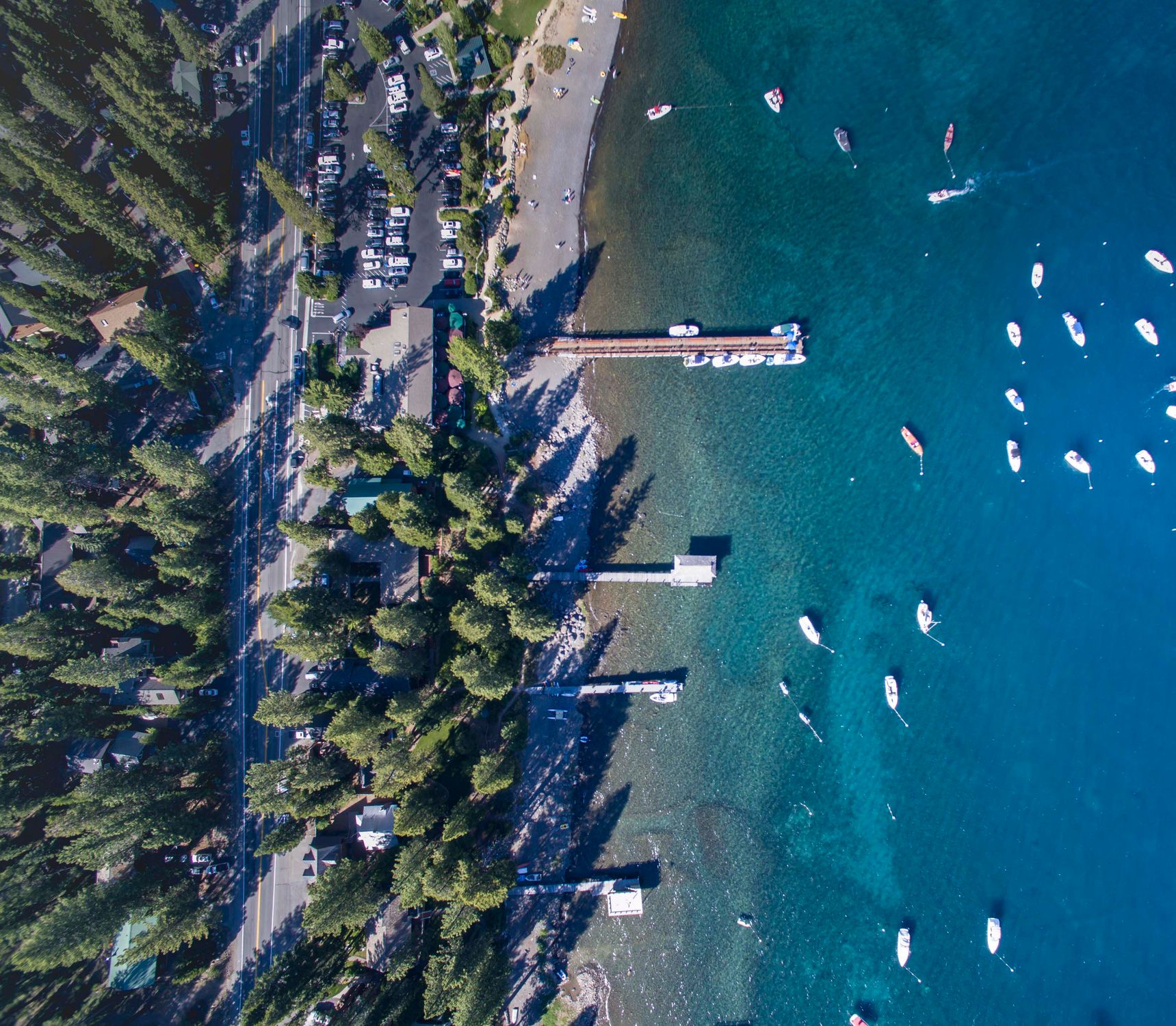 Aerial shot of Lake Tahoe with docks, beach, and boats visible from above.