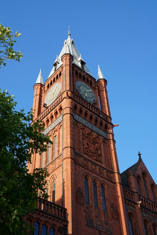 Free A historic Victorian red brick clock tower with ornate details under a clear blue sky. Stock Photo