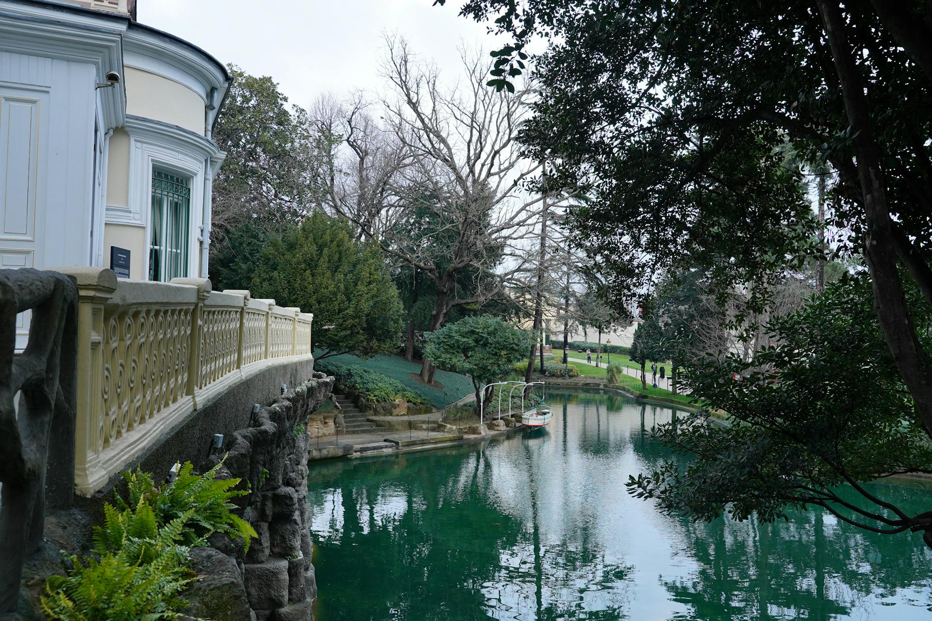 Picturesque view of a lakeside mansion with lush gardens and serene water reflections, perfect for tranquil escapes.