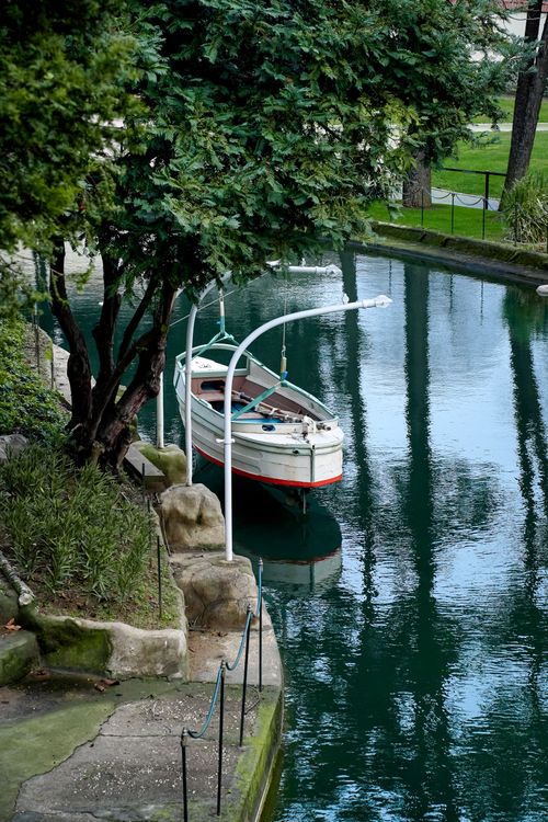 Free A peaceful scene of a boat moored in a lush, green canal setting, perfect for nature enthusiasts. Stock Photo