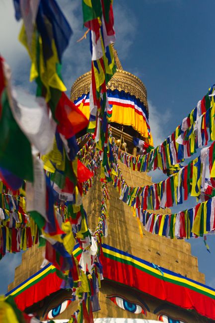 Vibrant prayer flags flutter around the iconic Boudhanath Stupa in Kathmandu, Nepal.