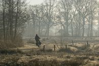 Cyclist on a foggy morning ride through the autumn countryside in Assen, Drenthe.