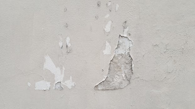 Detailed view of peeling paint on a concrete wall, showing decay and texture.