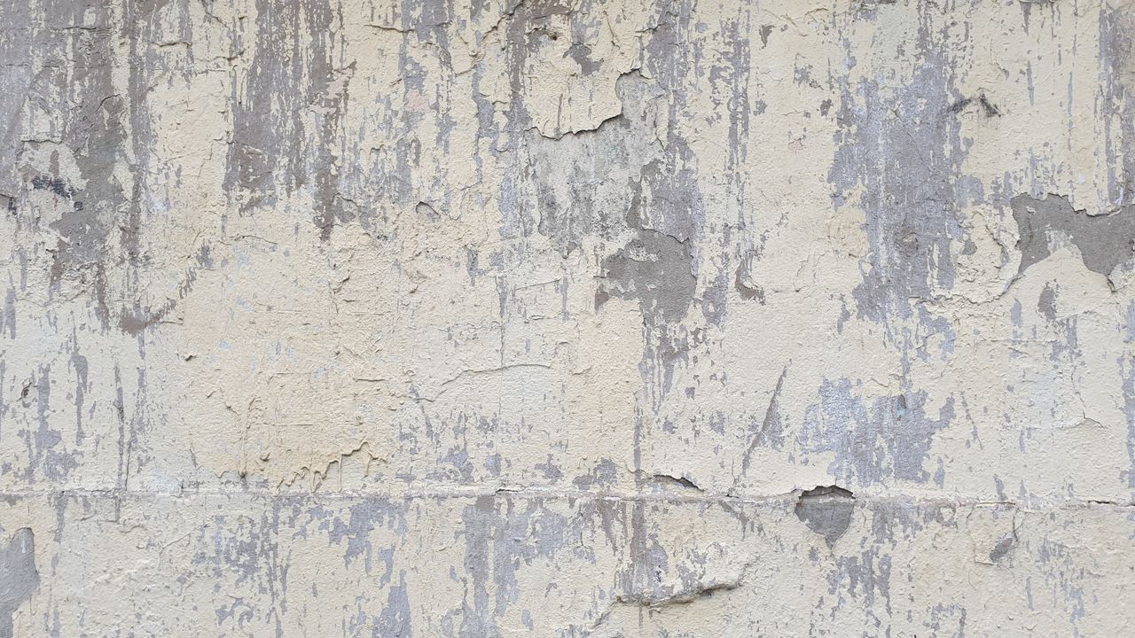 detailed texture of a weathered concrete wall featuring peeling paint