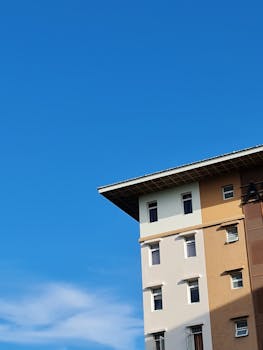 Corner view of a modern apartment building under a bright blue sky, ideal for urban lifestyle themes.