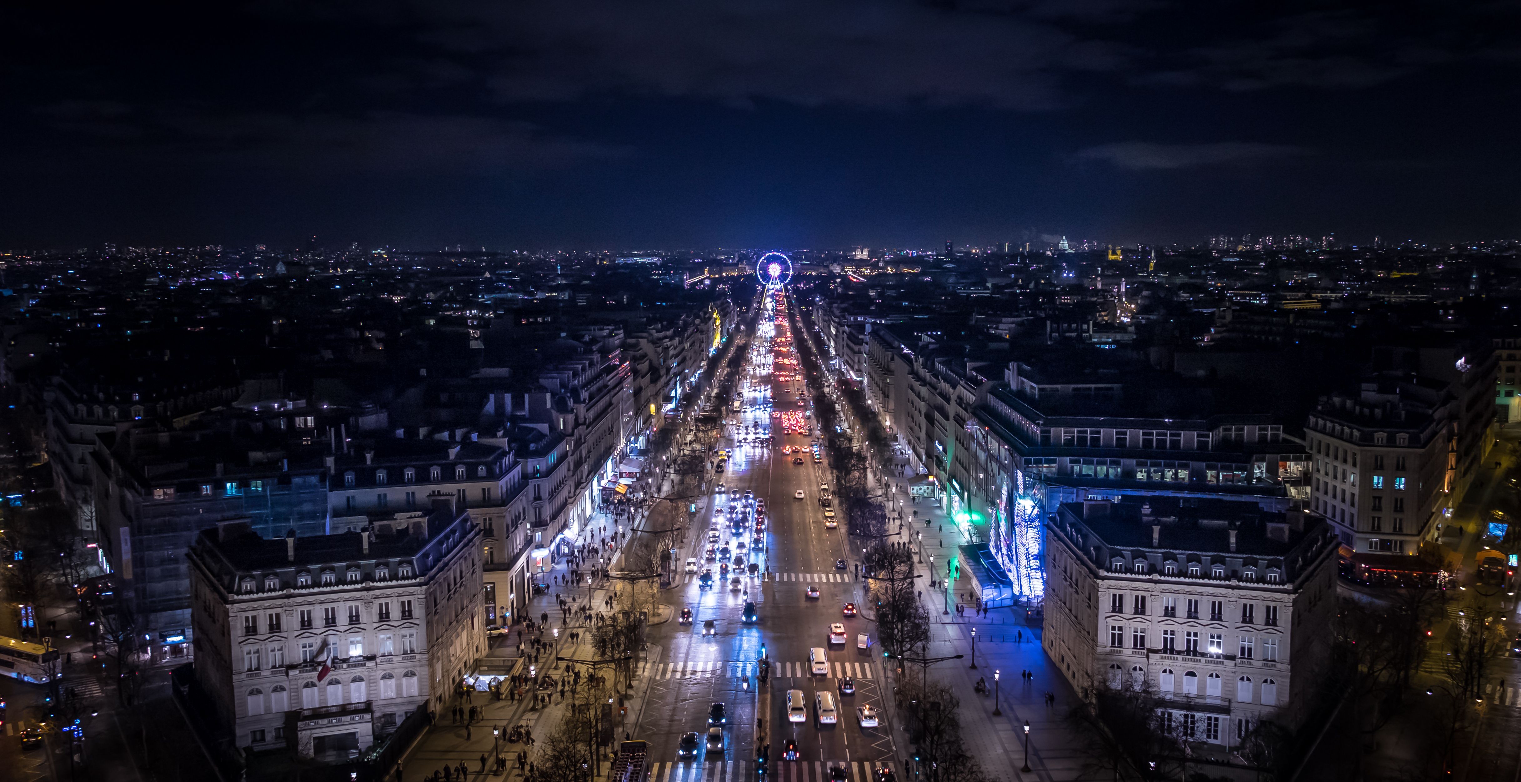 Stunning aerial view of a bustling Parisian avenue at night with glowing Ferris wheel. Stunning aerial view of a bustling Parisian avenue at night with glowing Ferris wheel.