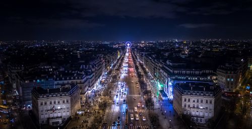 Free Stunning aerial view of a bustling Parisian avenue at night with glowing Ferris wheel. Stock Photo