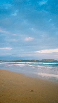 Tranquil beach scene in Cabo Frio, Brazil with calm waves and blue sky.