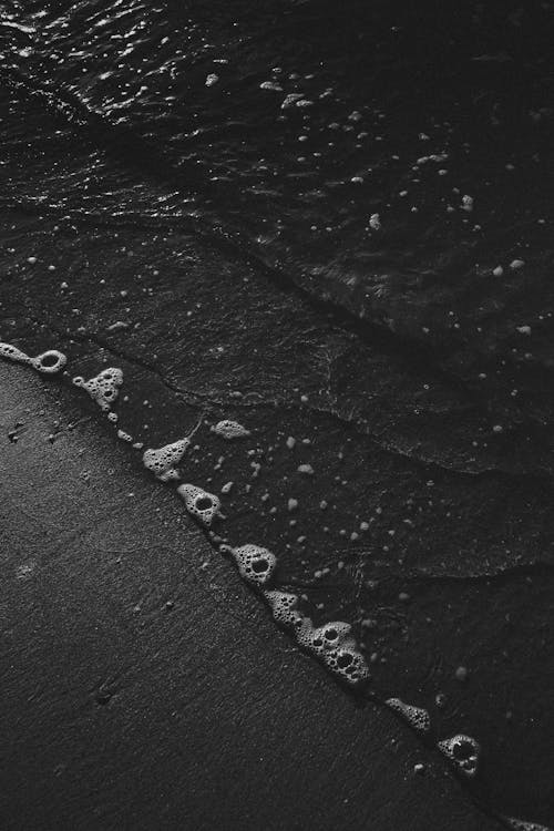 岸に打ち寄せる海の波のグレースケール写真