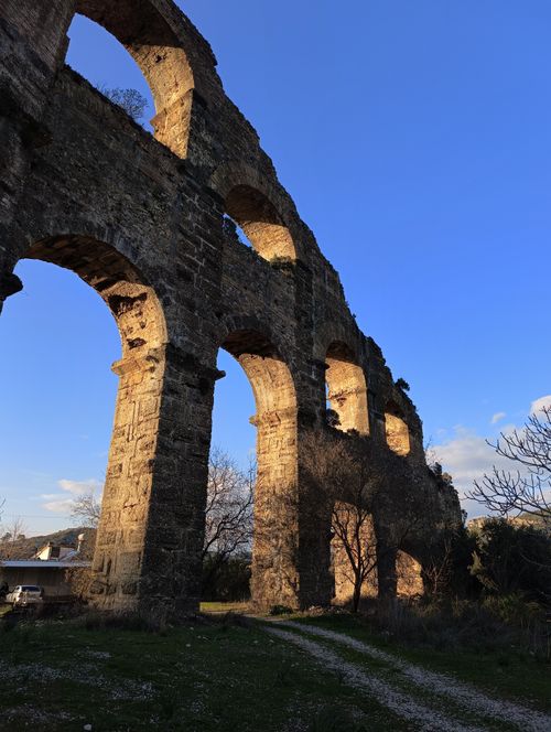 Free Majestic ancient stone aqueduct ruins illuminated by the warm glow of sunset. Stock Photo