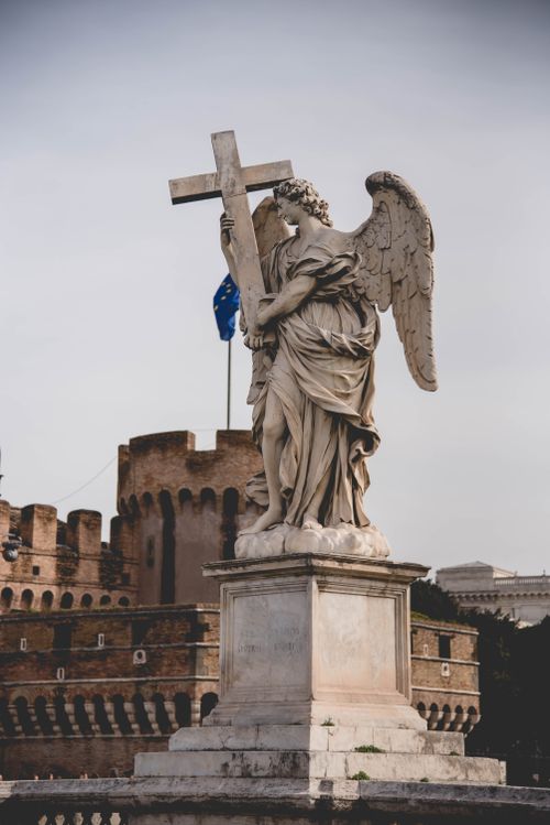 Free A majestic angel statue holding a cross on Ponte Sant'Angelo in Rome, Italy. Stock Photo