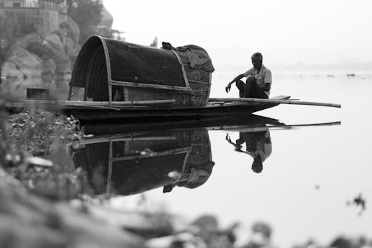 A contemplative man sitting on a boat reflects in the calm waters.