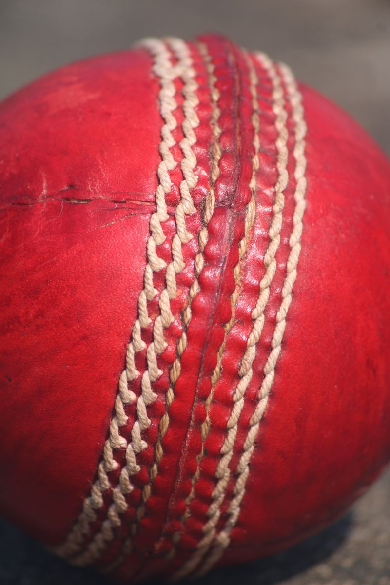 Close-up of a red leather cricket ball showing seam and stitching detail