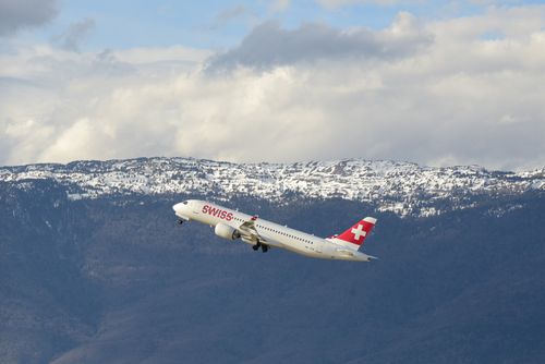 Free A Swiss airplane taking off with snow-capped mountains in the background in Geneva, Switzerland. Stock Photo