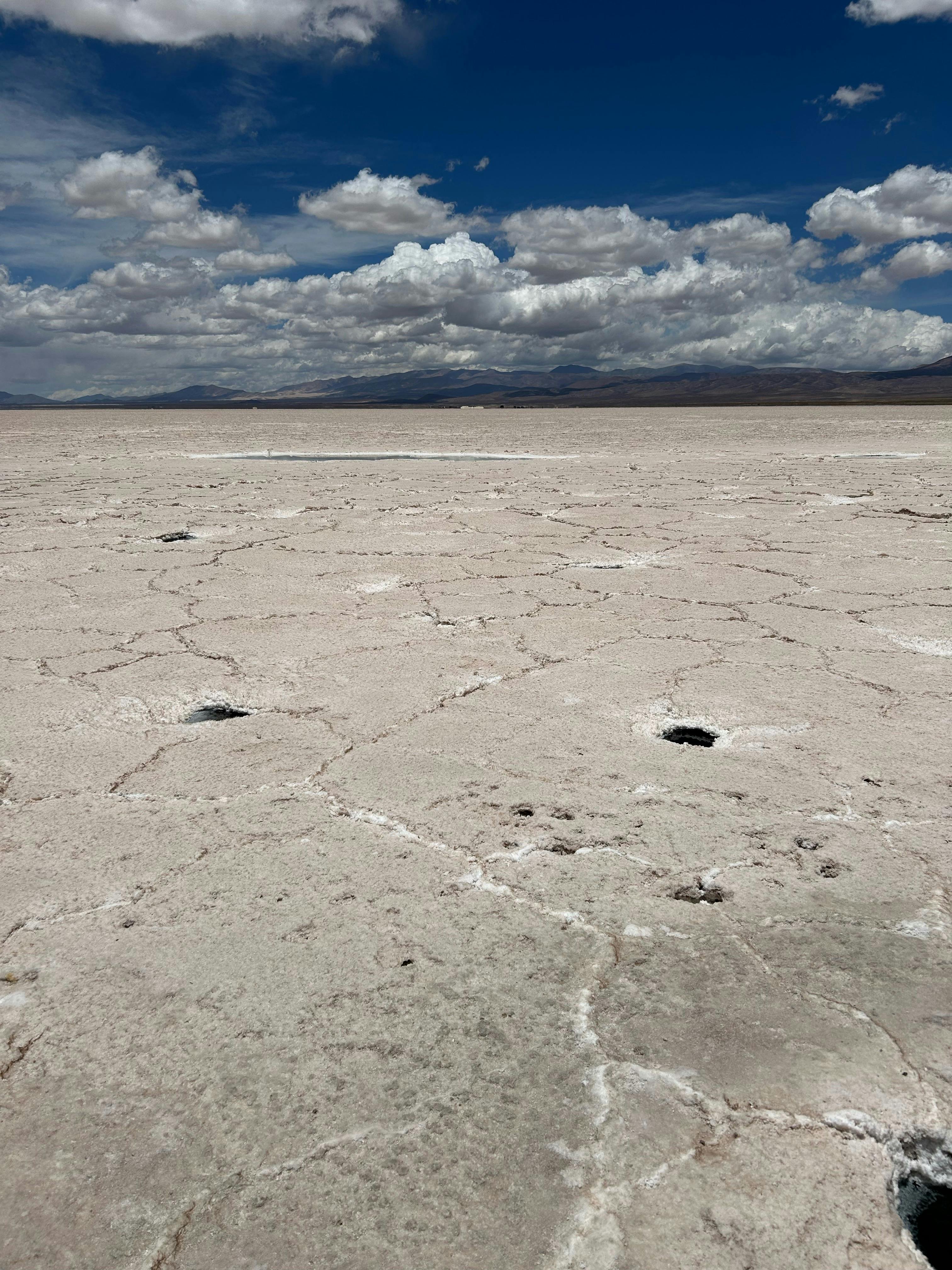 Expansive salt flat with cracked surface under a dramatic cloudy sky.