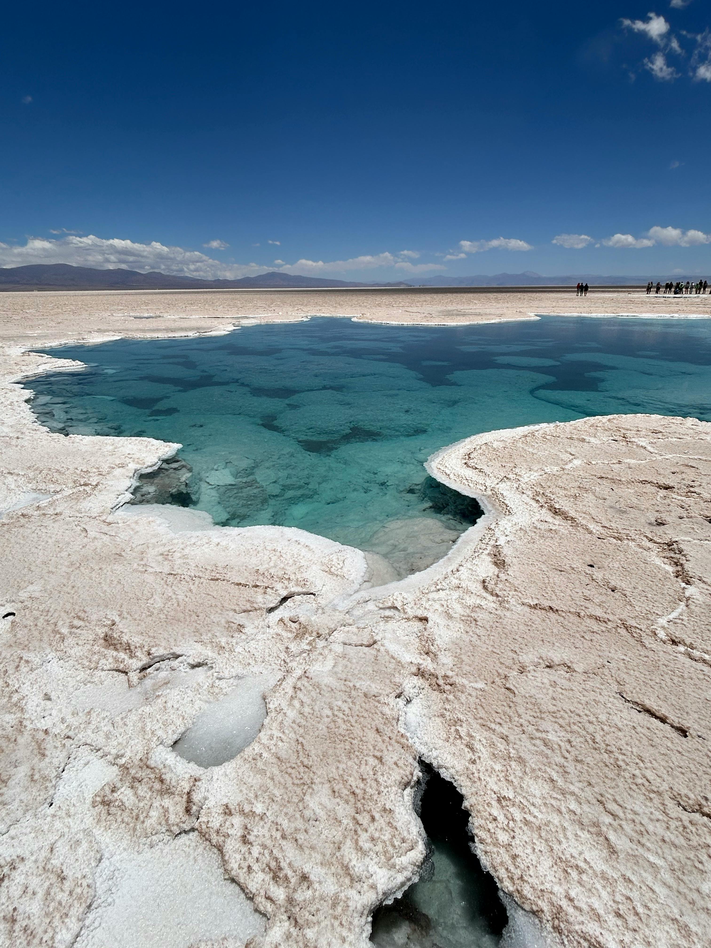 Breathtaking view of a serene salt flat with turquoise lagoon under a clear blue sky.